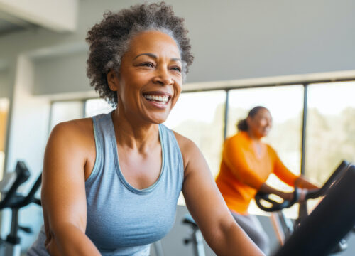 Photo of a middle aged African American woman on stationary exercise bike at gym, maintaining a healthy lifestyle, focused on exercises